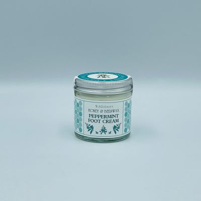 Screw top glass jar of honey and beeswax peppermint foot cream wrapped with a branded sticker, white background.